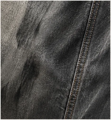 Detail of black denim contrast, twill and surface sheen.