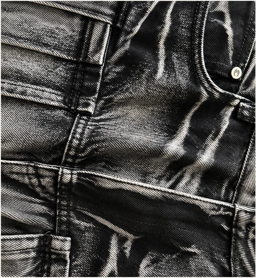 Close-up of black denim with high-contrast highlights, sculptural creases and a subtle surface sheen.