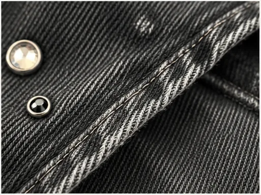 Detail of metal embellishment and controlled distressing on black denim.