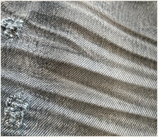 Detail of whisker lines and worn-in fade on vintage blue denim.