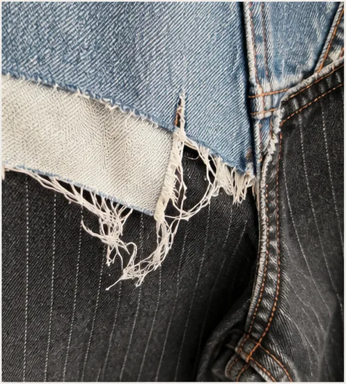 Detail of mixed denim panels, raw edge and contrast stitching.