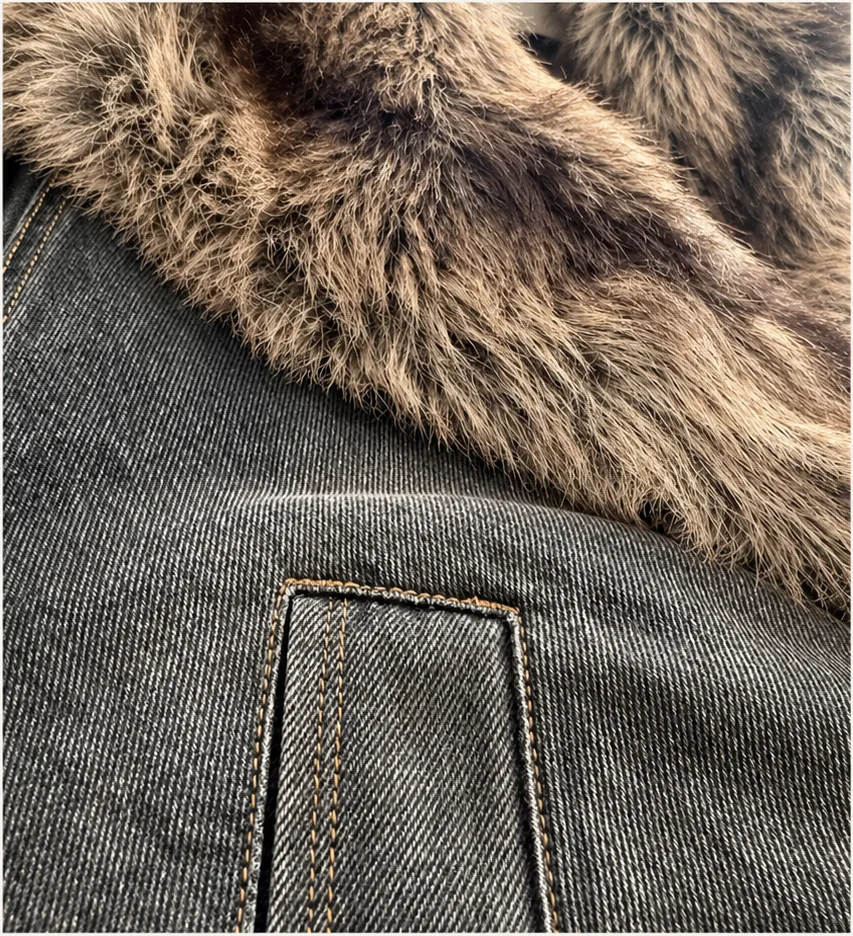 Close-up of washed charcoal denim with visible twill, contrast stitching and a textured brown pile trim.